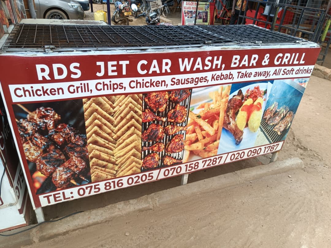 Outdoor grill with a sign for RDS Jet Car Wash, Bar & Grill advertising food.