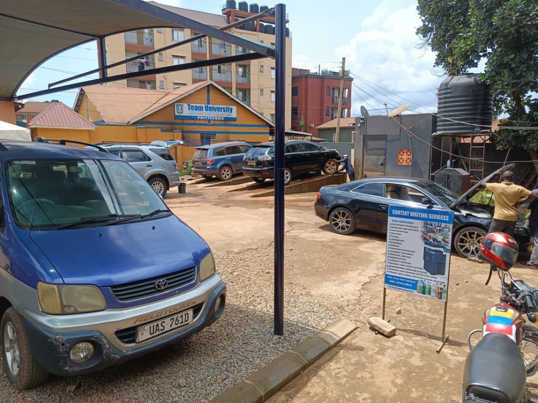 Blue Toyota van parked in a gravel lot with cars being repaired near Team University.